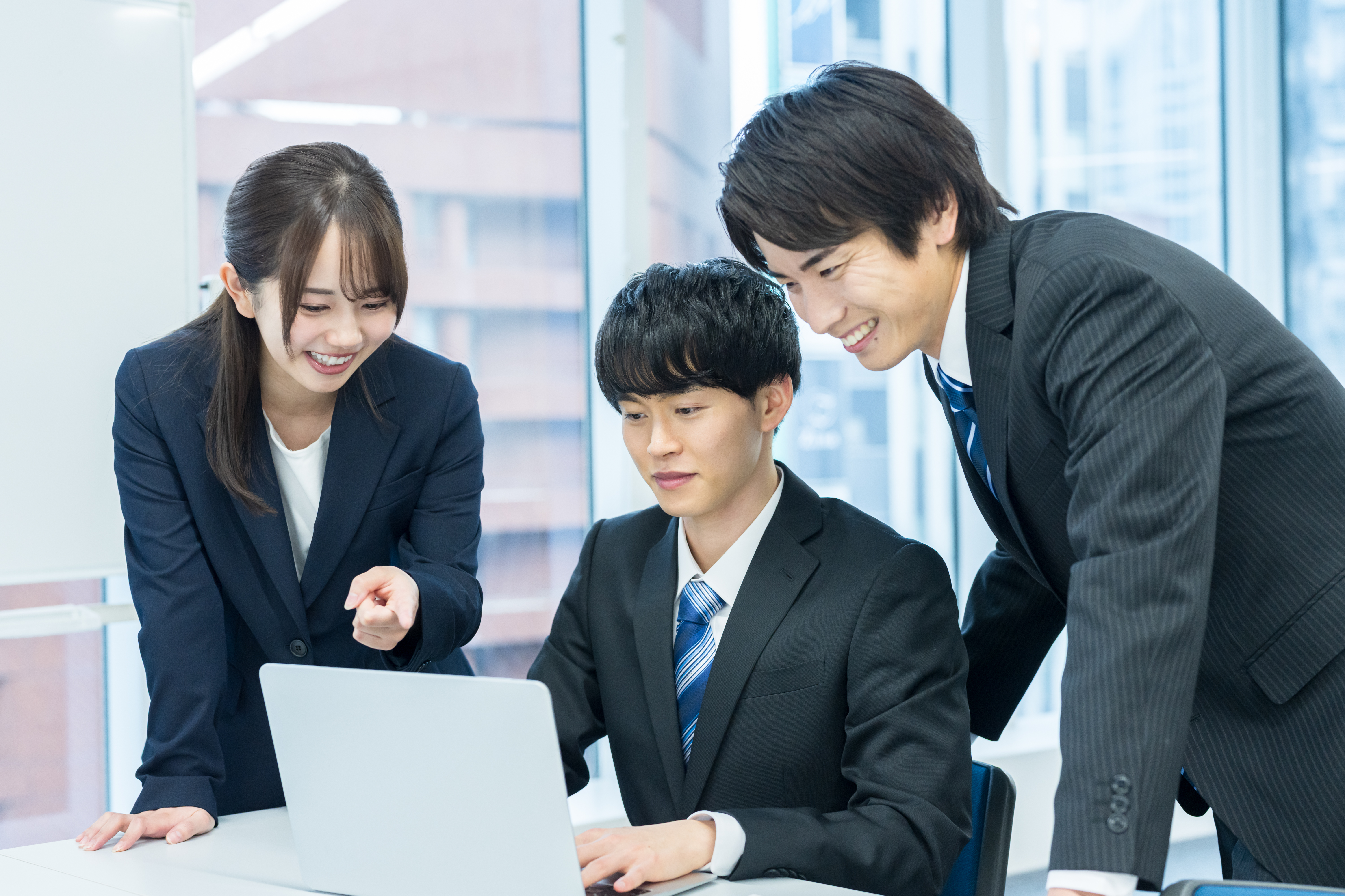 インハウスSEO内製化後のチーム運用。PC画面でデータを確認し、改善ポイントを話し合う社内スタッフ。