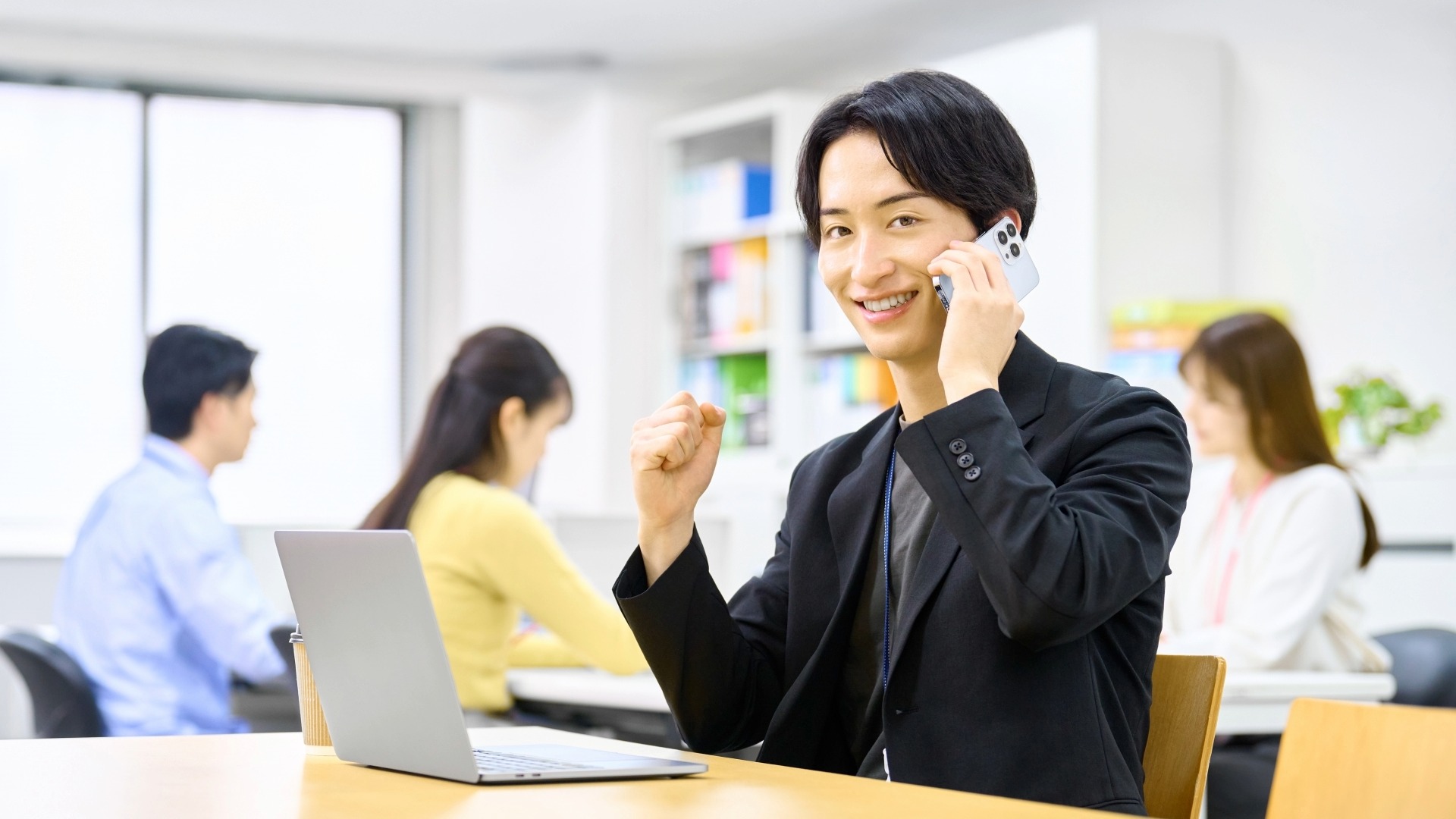 オウンドメディアの成果を喜び、電話で報告しながらガッツポーズをする運営担当者の男性。