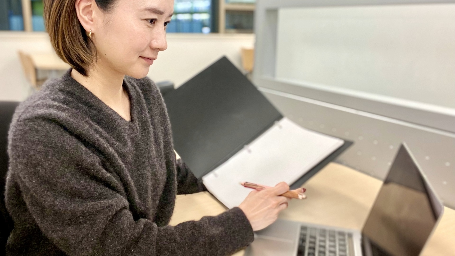 オウンドメディアの運用ルールや目的別の指標がまとめられた資料を確認しながら、PCで着実に業務を遂行する様子。