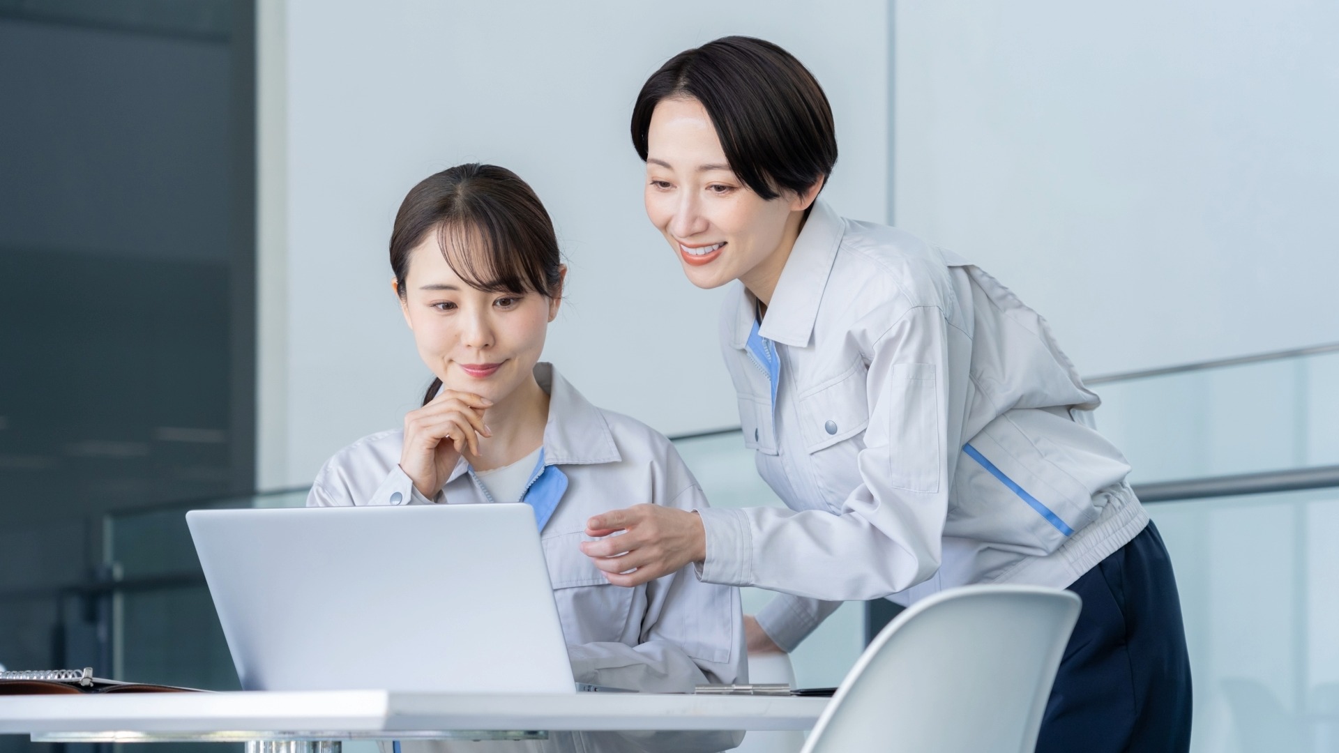 現場の声をオウンドメディアに反映させるため、作業服のスタッフがPCでコンテンツの方向性を打ち合わせする光景。