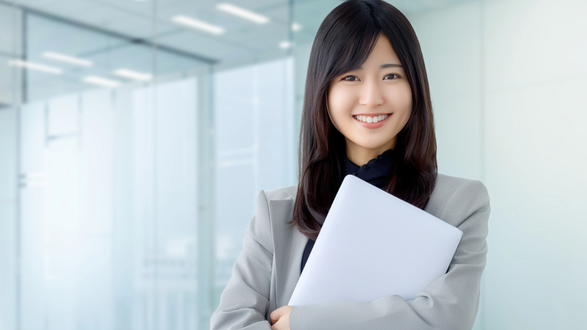 オウンドメディア成功に向けてノートPCを抱える、プロフェッショナルな女性メディアディレクター。