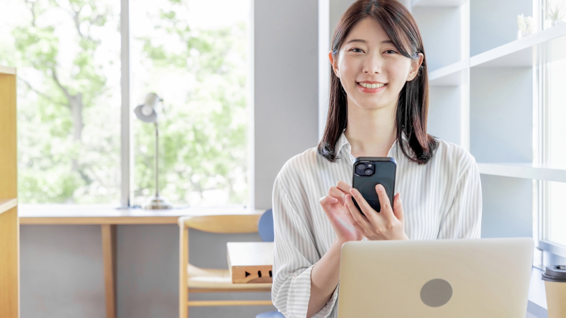 オウンドメディアの記事公開後に、スマートフォンでSNSの反応やモバイルでの表示を確認し、KPI達成を喜ぶ担当者。