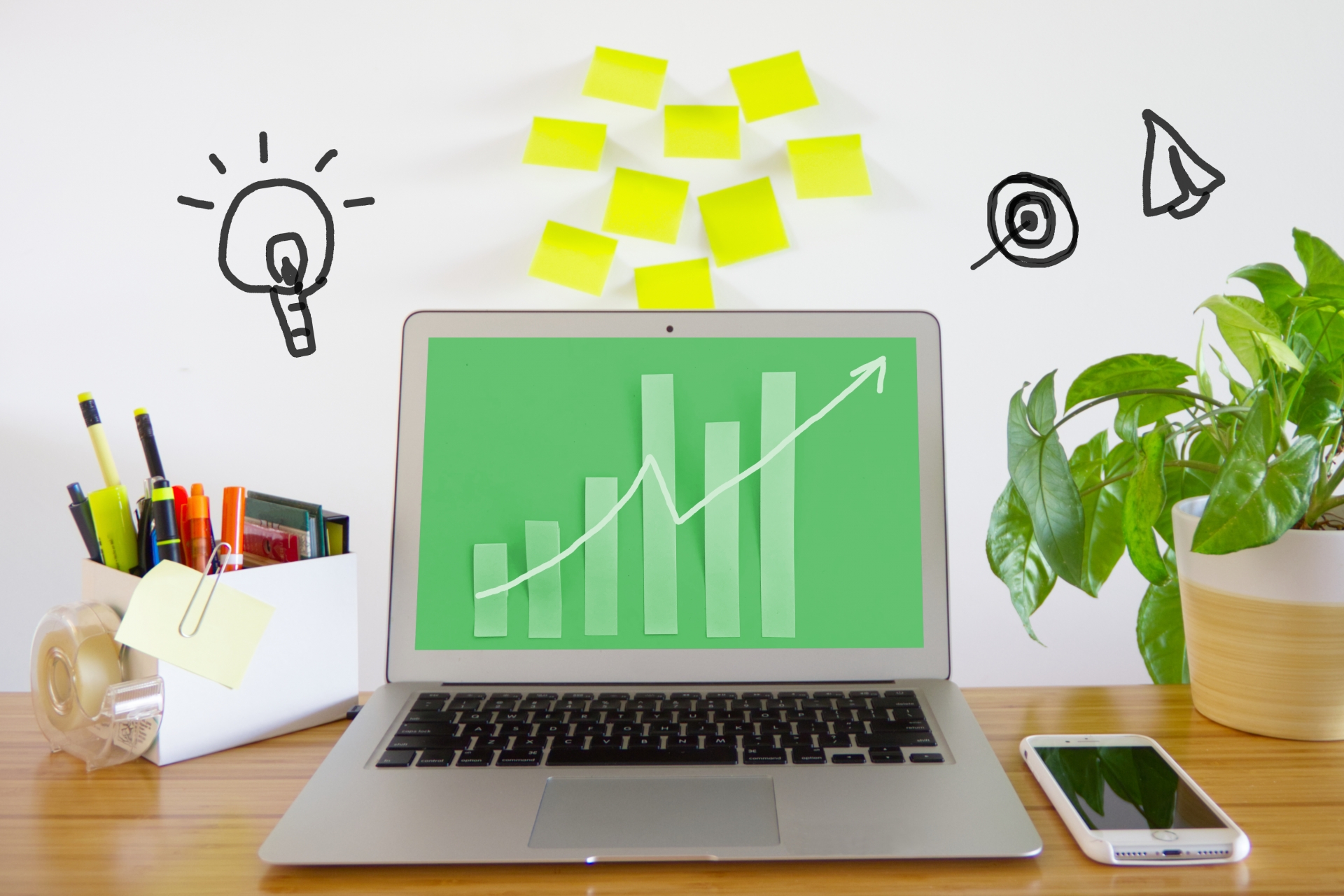 BtoBオウンドメディア導入による右肩上がりの成長率と成果をイメージした、ノートパソコンとビジネス分析のデスク風景。