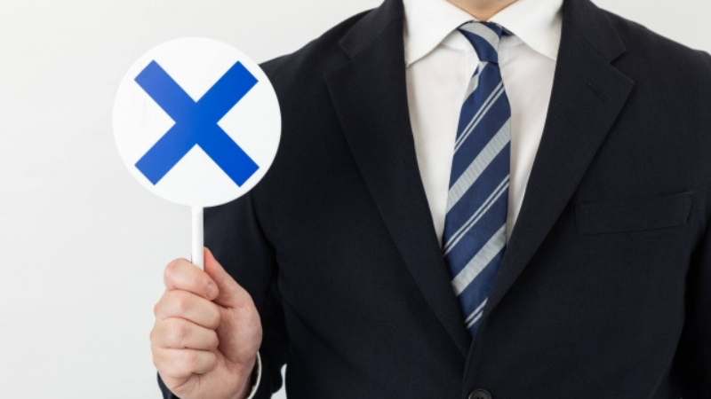 オウンドメディア運営で避けるべき失敗原因や、やってはいけないNG行動を提示するスーツ姿の男性