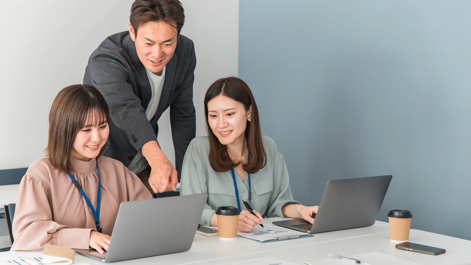 オウンドメディア運用の成功事例を生み出すチーム体制のイメージ。外注先とのスムーズな連携や、社内での手順確認・戦略会議を行っているビジネスシーン。