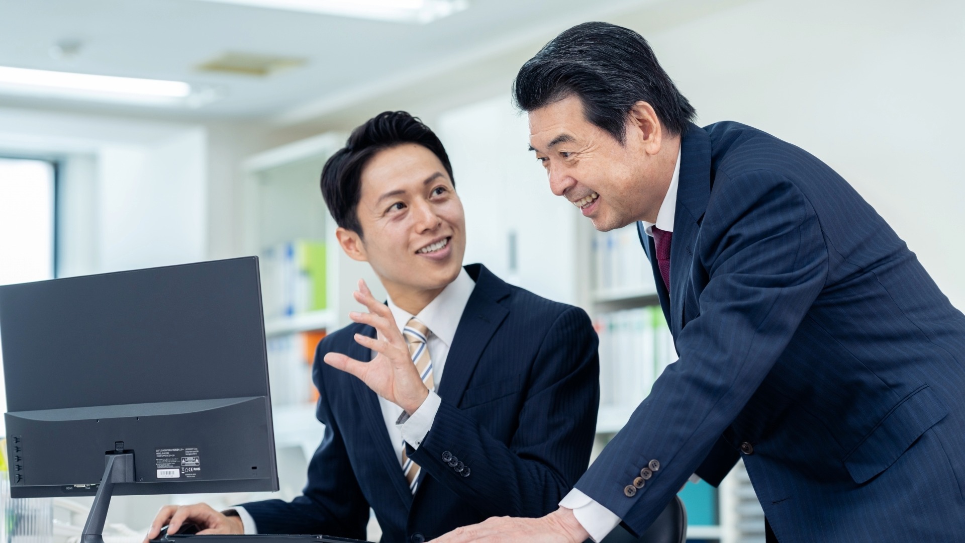 BtoCマーケティングにおけるオウンドメディア運用の事例を上司に説明する男性社員のイメージ。