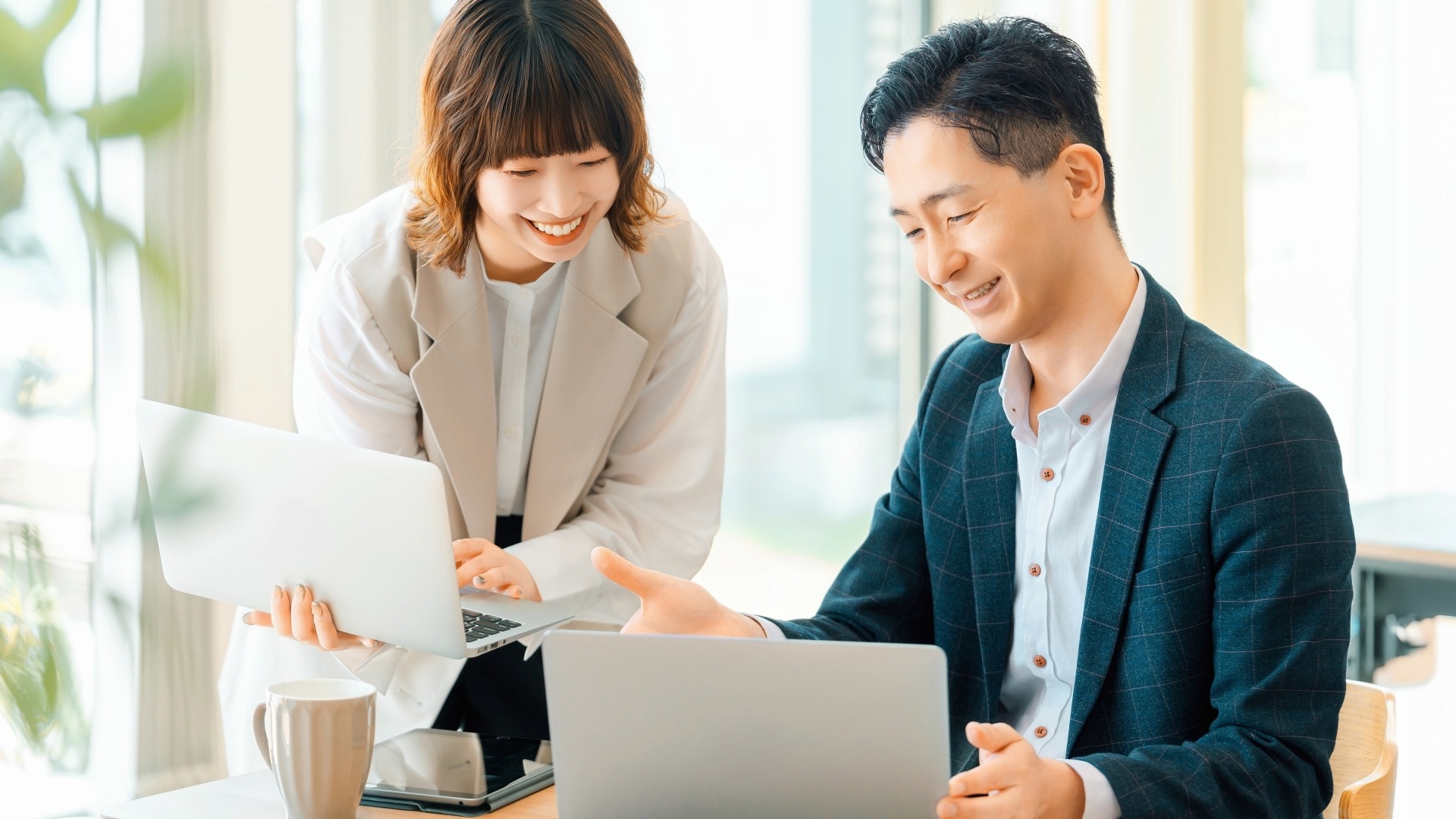 ウェブサイトの信頼性を高める外部対策について、PC画面を見ながら談笑するビジネスパーソン。