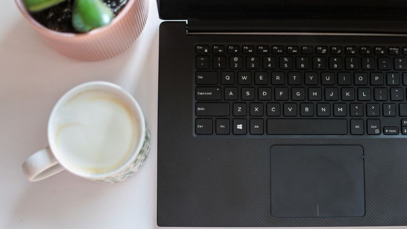 オウンドメディア運用を継続するための効率的な執筆環境。ノートパソコンとコーヒーをデスクに用意し、記事作成に集中するワークスタイル。